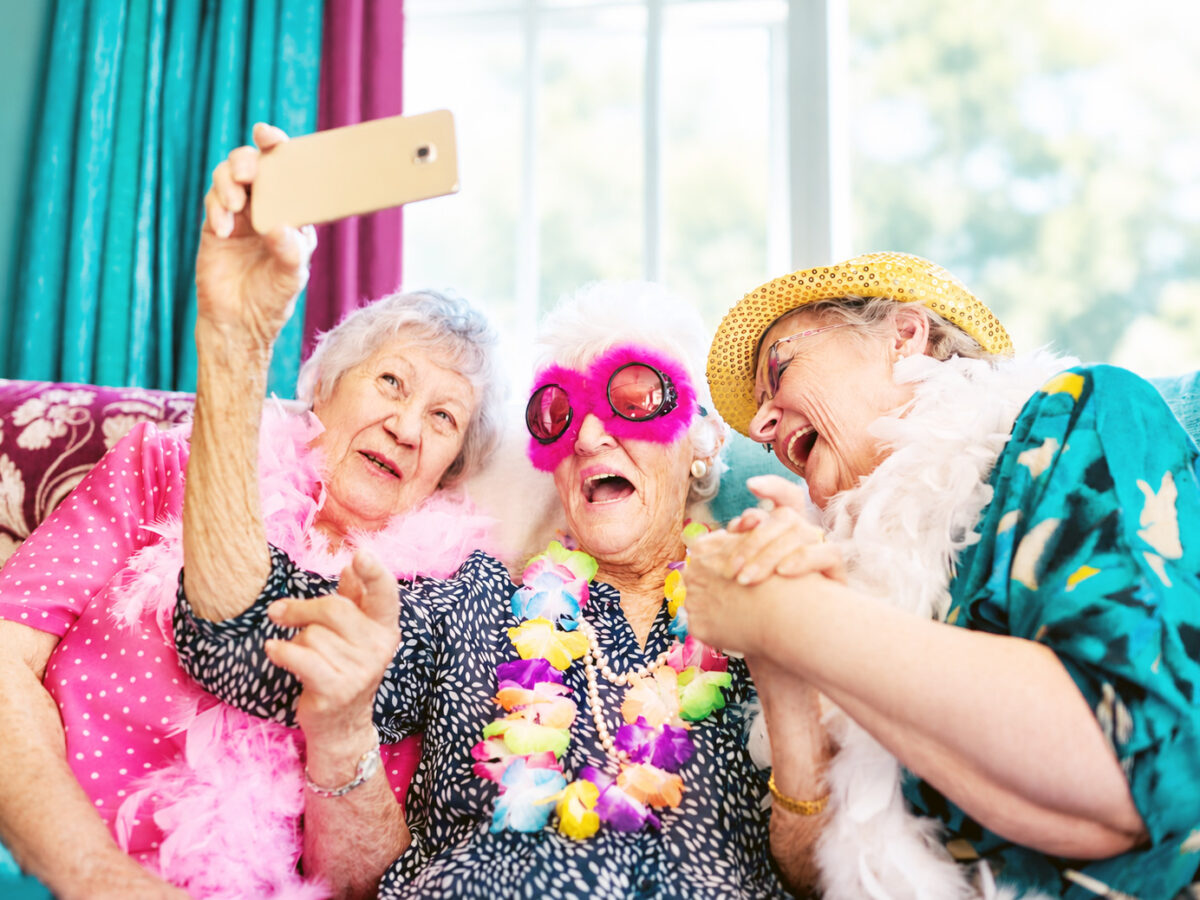 Three older women laughing together while taking a selfie, illustrating the joyful moments care home teams help make possible.